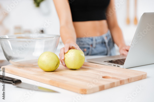 Cropped image of woman with apple and laptop