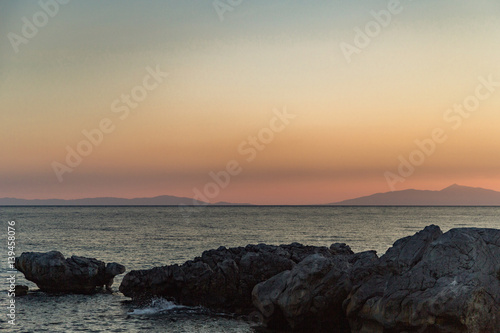Evening on orange sunset on the sea coast in the summer among the rocks.