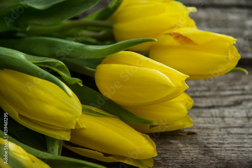 Yellow tulips on rustic old wood table