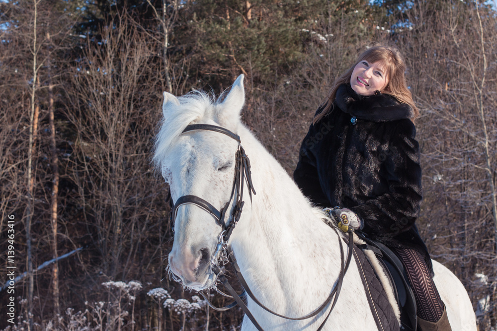 Fototapeta premium Nice girl and white horse in a forest in a winter