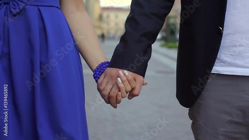 Young lovely couple holding hands and walking in a city street