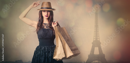 beautiful young woman with shopping bags standing in front of wonderful paris background