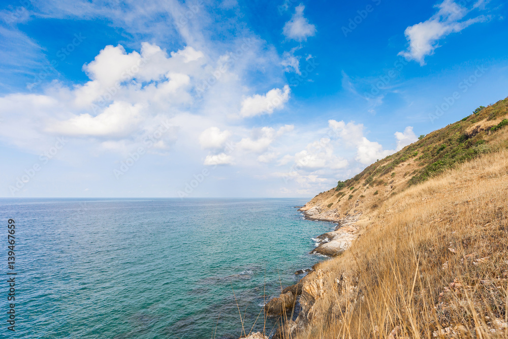 Beautiful seascape with rocks and meadow in cloudy blue sky