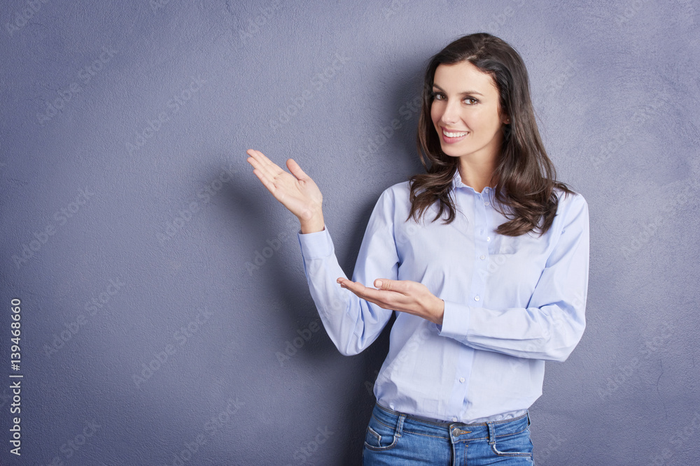 How do you like it. Close-up shot of a smiling young woman pointing upwards to copy space while standing against a grey wall. How do you like it. Close-up shot of a smiling young woman pointing upwards to copy space while standing against a grey wall.