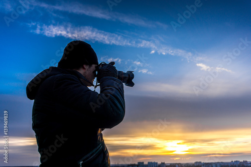 Photographer takes shot of sunset at background of clourful dramatic sky
