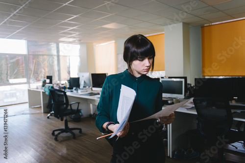 Young stylish office worker with a serious expression reviewing business documents. Against the background of the modern office. Business concept