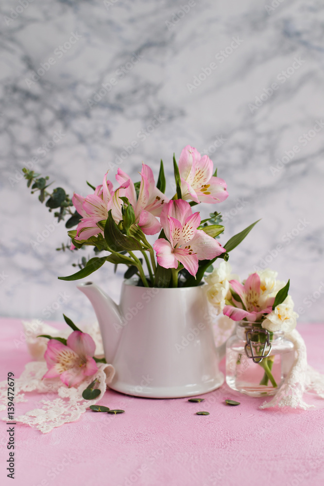 Pink flowers in a teapot on a light background Pink flowers in a teapot on a light background