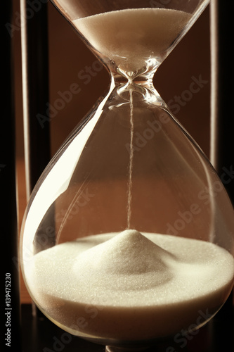 Black hourglass with white sand, closeup