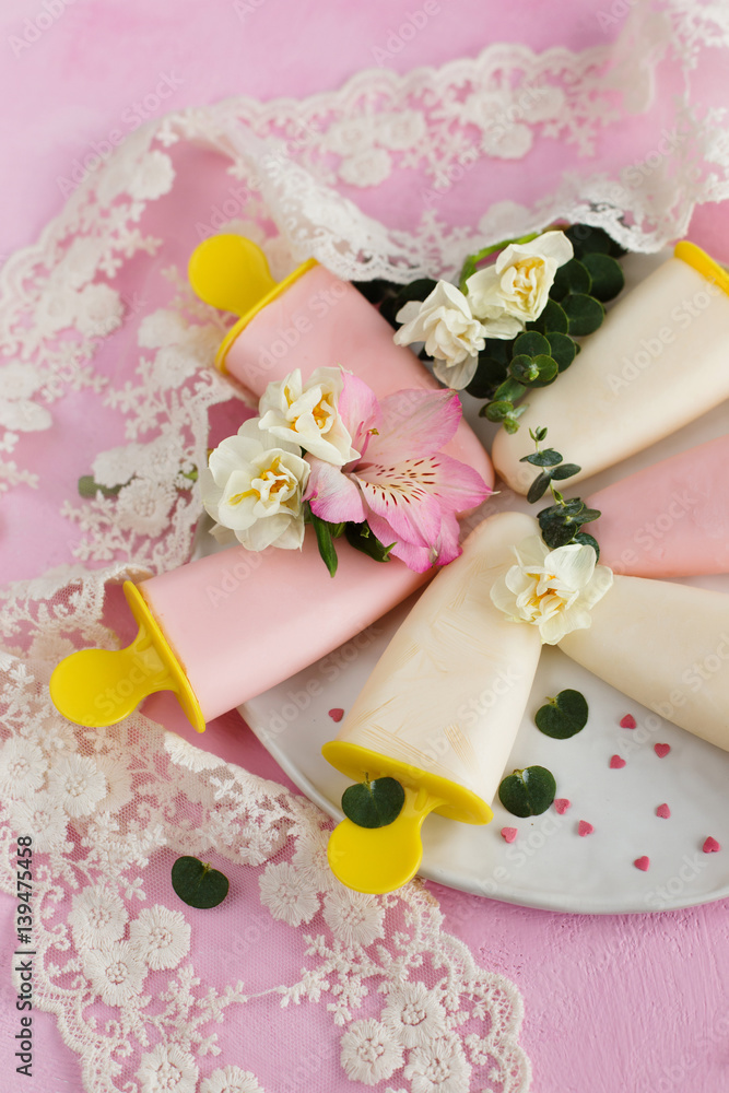 Yoghurt ice cream, decorated with flowers on a pink background (close-up) Yoghurt ice cream, decorated with flowers on a pink background (close-up)
