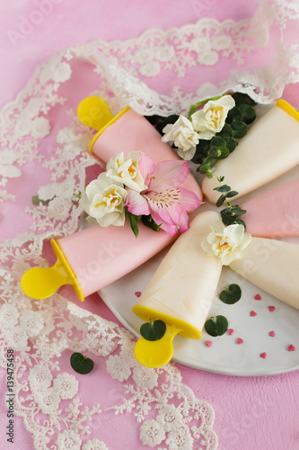 Yoghurt ice cream, decorated with flowers on a pink background (close-up)