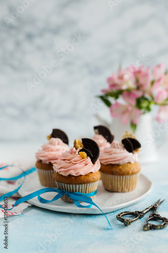 Pink cupcakes, decorated biscuits on a light background