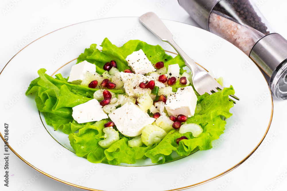 Lettuce, celery, feta, pomegranate seeds on a white Lettuce, celery, feta, pomegranate seeds on a white