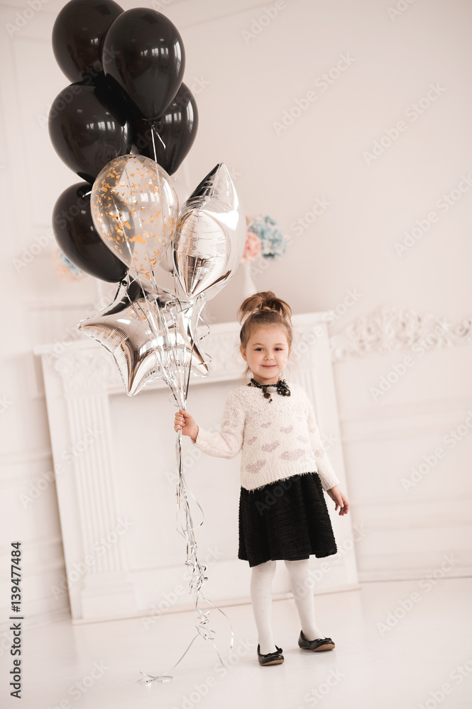 Smiling kid girl 5 6 year old holding balloons wearing black dress