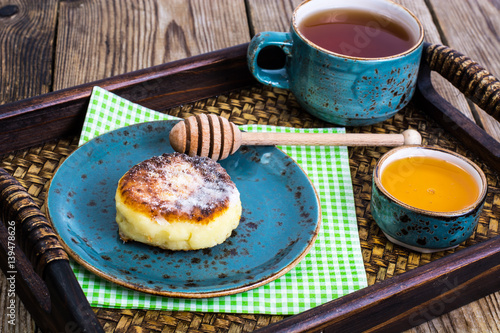 Pancakes with honey on vintage bowl on wooden tray photo