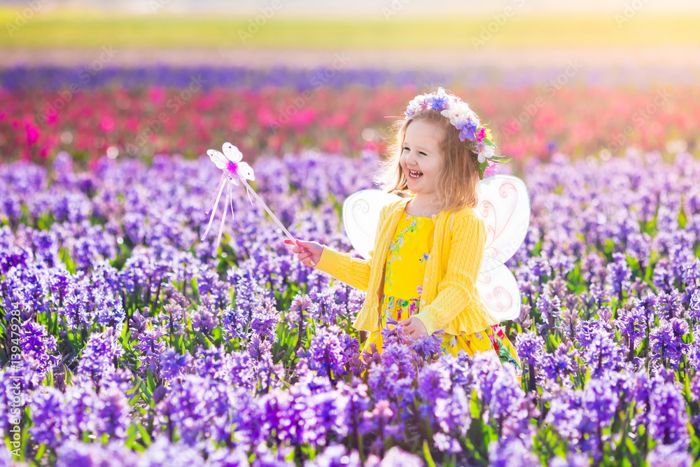 Little girl in fairy costume playing in flower field Little girl in fairy costume playing in flower field