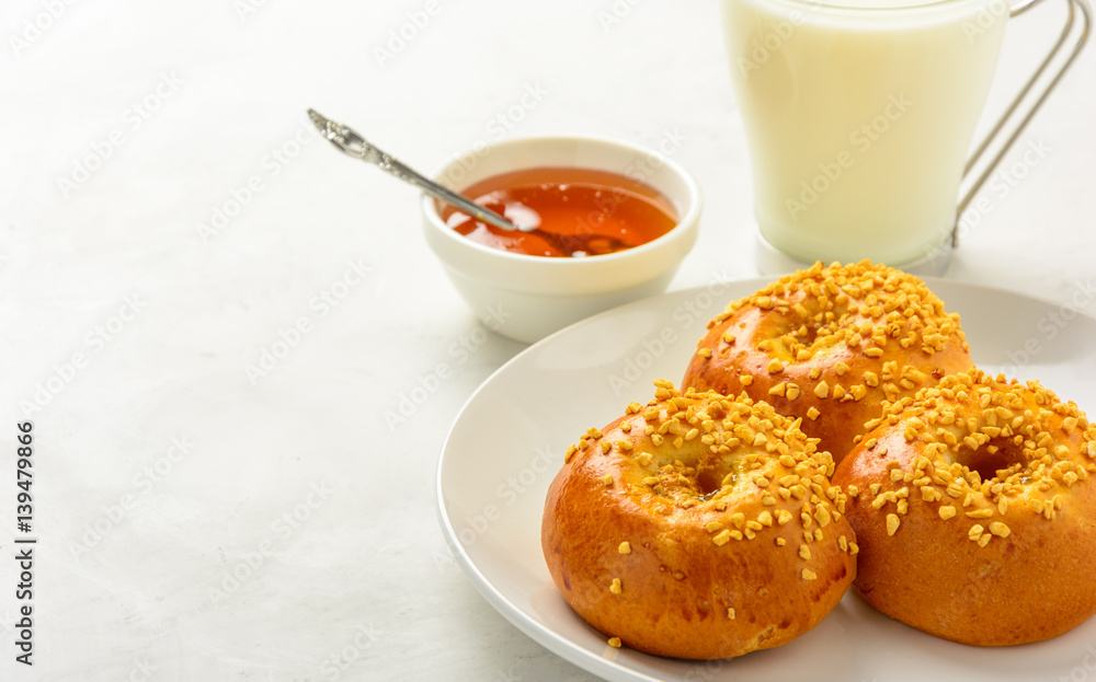 Delicious and healthy breakfast of brioche buns with milk and honey on a light background. Copy space, soft fokus. Delicious and healthy breakfast of brioche buns with milk and honey on a light background. Copy space, soft fokus.