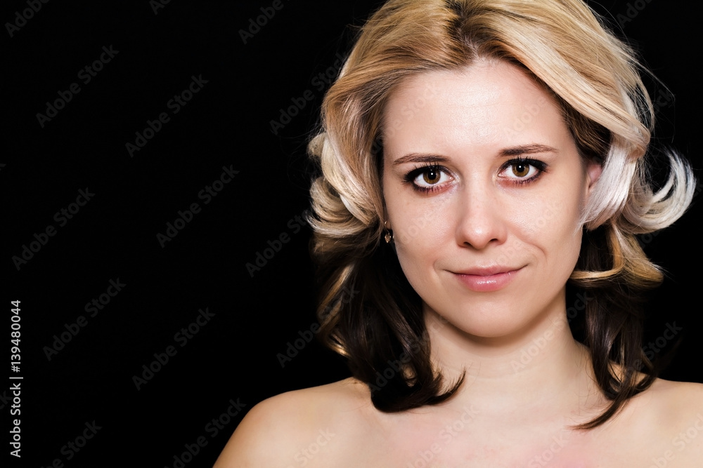 Close-up of a woman with blonde curls on a dark background smiling