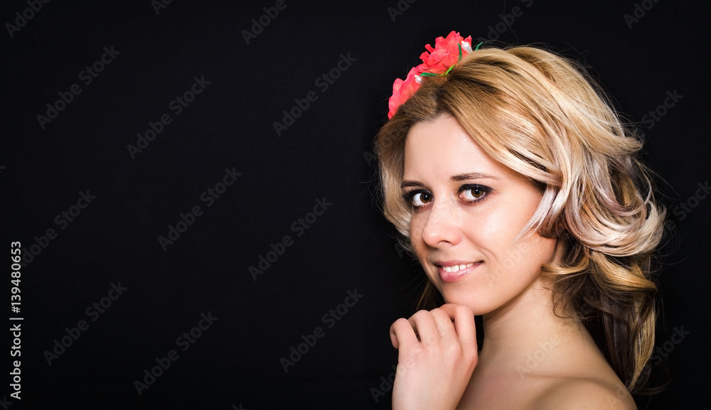Woman with blonde laying and rimmed with red flowers on a dark background smiling. Close-up. Space for text
