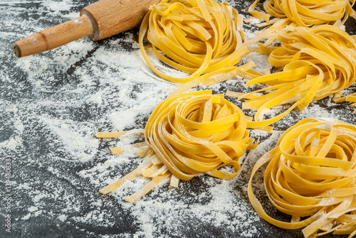 Home fresh raw pasta, paglia e fino, on the kitchen table black concrete, sprinkle with flour. With a rolling pin, eggs, close view, copy space