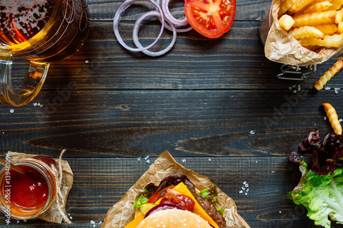 Fresh delicious burgers with french fries, sauce and beer on the wooden table top view