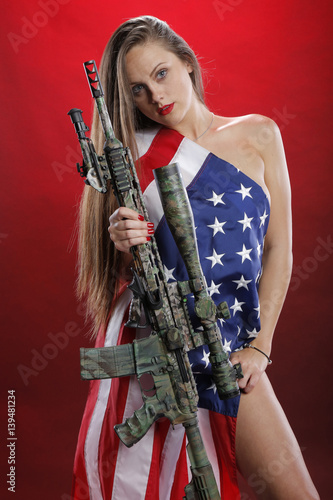 Woman carrying a sniper rifle and wearing an American flag