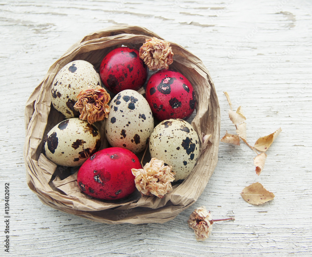 Easter red and white quail eggs in a decorative nest on the wooden old painted table. Easter concept Easter red and white quail eggs in a decorative nest on the wooden old painted table. Easter concept
