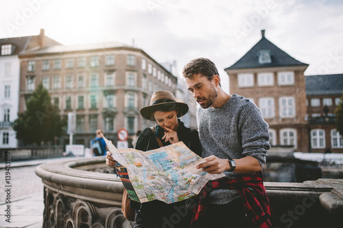 Young tourist couple exploring a city map.