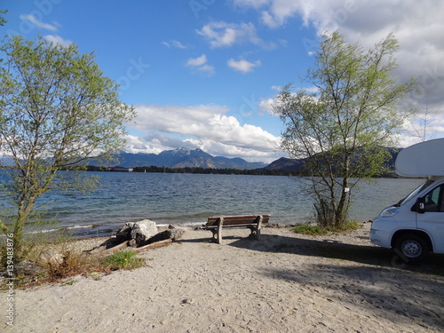 Chiemsee with blue sky, trees and caravan