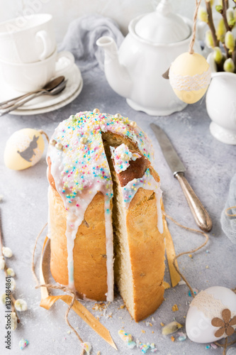 Easter composition with orthodox sliced sweet bread, kulich and eggs on light background. Holidays breakfast.