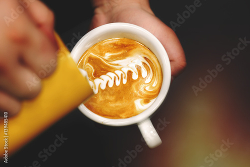 Cup of coffee. Latte art made by barista focus in milk and coffee. Vintage color