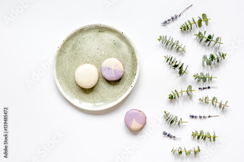 Trendy design with macaroons on plate, eucalyptus and lavander top view