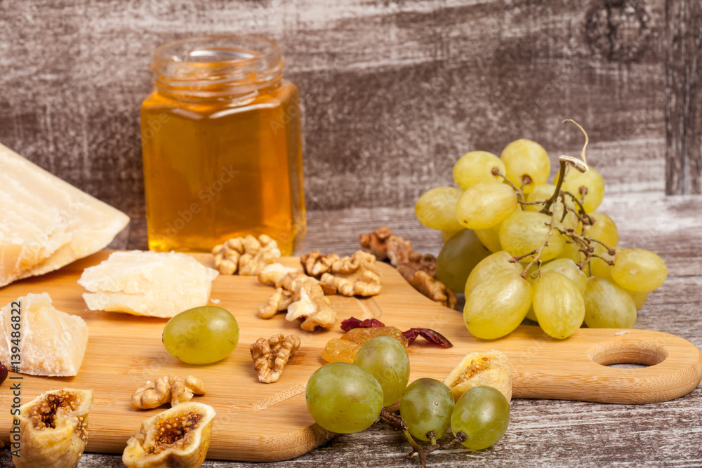 Cheese, honey and grape on wooden background