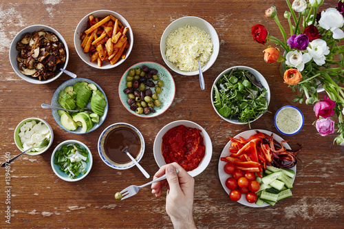 person took an olive with a fork variety of salads photo