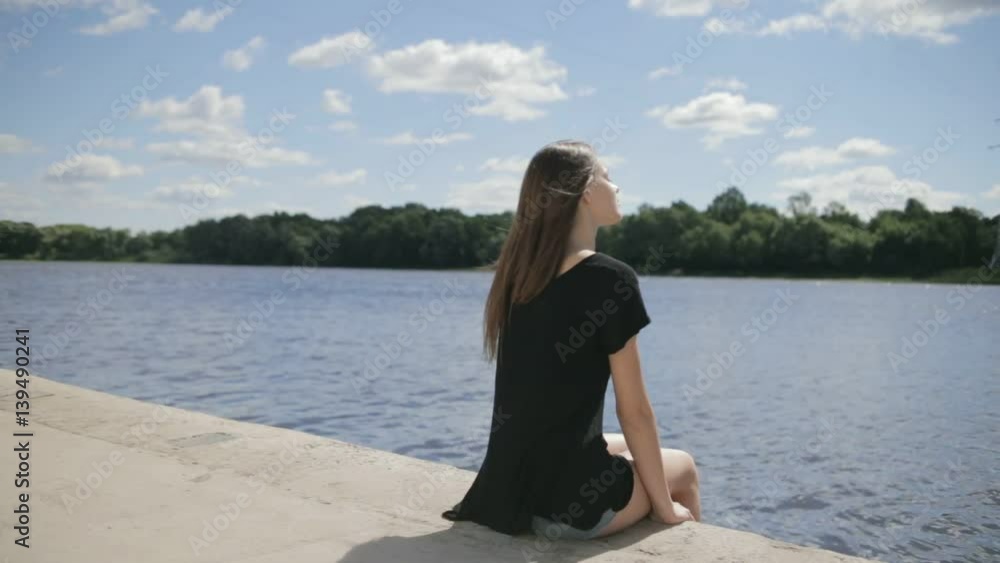 Young pretty woman sitting near river with closed eyes Young pretty woman sitting near river with closed eyes