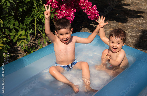 niños jugando en una piscina hinchable en verano photo