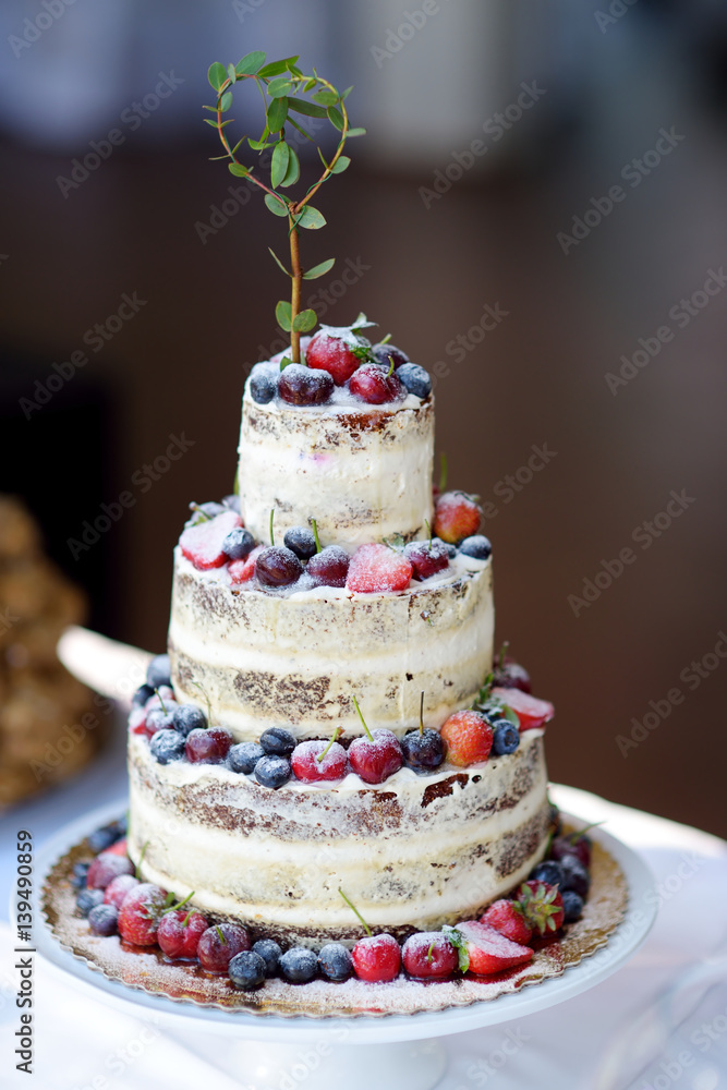 Delicious chocolate wedding cake decorated with fruits and berries
