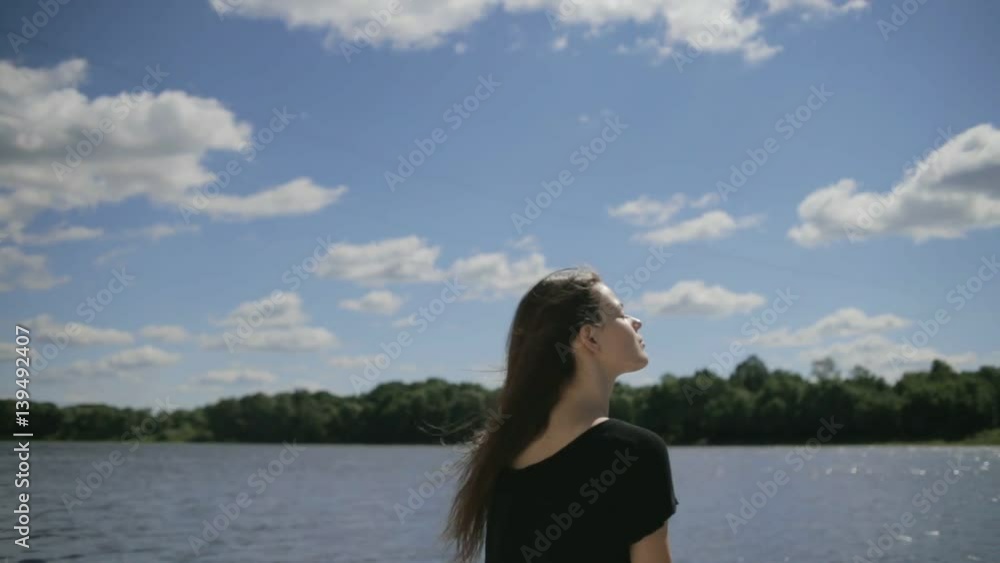 Young pretty woman sitting near river with closed eyes Young pretty woman sitting near river with closed eyes