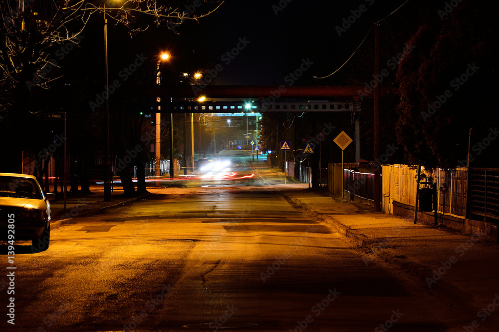 Nocna ulica oświetlona lampami i samochody w ruchu. - obrazy, fototapety, plakaty 