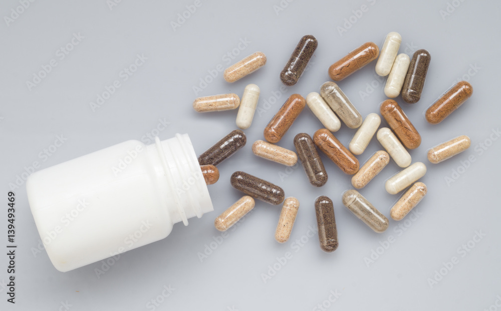 Naklejka premium Medicinal capsule spill out of a plastic bottle on a light surfa