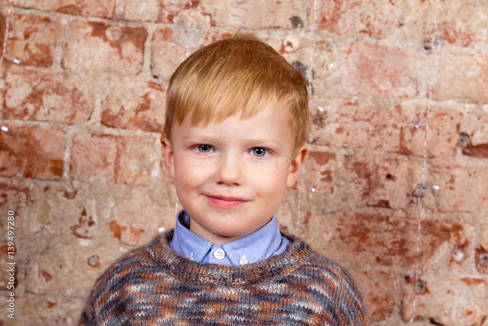 Little boy with red hair on the brick wall background Little boy with red hair on the brick wall background