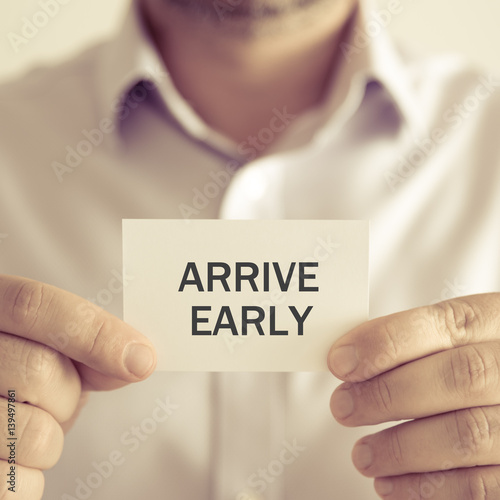 Businessman holding ARRIVE EARLY message card