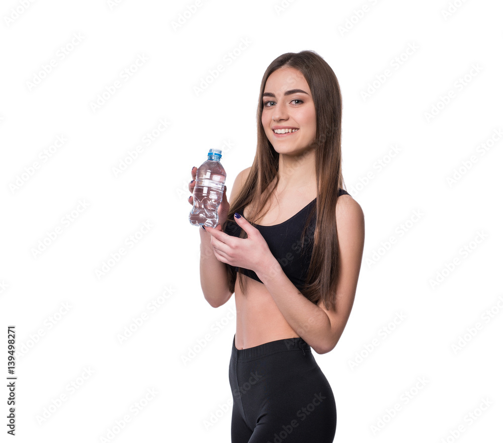 Positive female fitness model after workout holding a bottle of pure water over white background. Positive female fitness model after workout holding a bottle of pure water over white background.