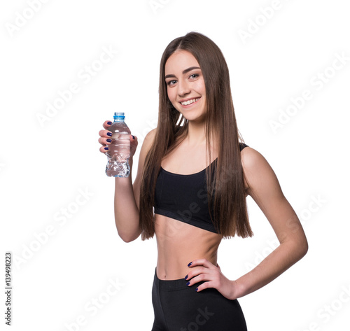 Positive female fitness model after workout holding a bottle of pure water over white background.