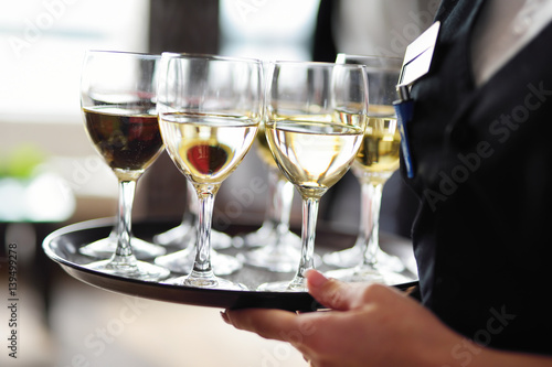 Принти на полотні Waitress holding a dish of champagne and wine glasses at festive event