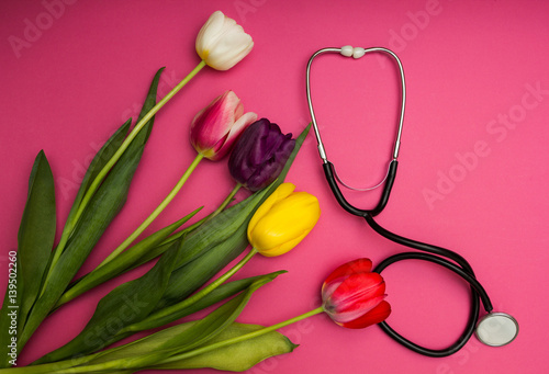 Fototapeta Naklejka Na Ścianę i Meble -  Stethoscope and colorful tulips on a pink background.