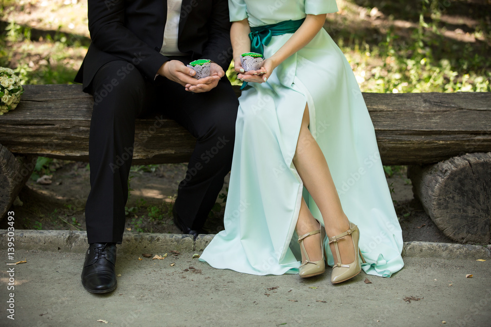 Man and woman holding green cupcakes in park. Green wedding or