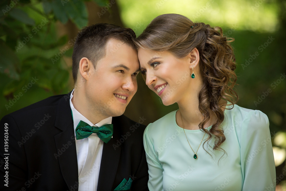 Wedding couple, elegant groom with green bow and beautiful bride in mint dress looking at each other in green park Wedding couple, elegant groom with green bow and beautiful bride in mint dress looking at each other in green park