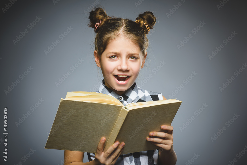 angry or stressed girl with book. child on grey background. studies concept angry or stressed girl with book. child on grey background. studies concept