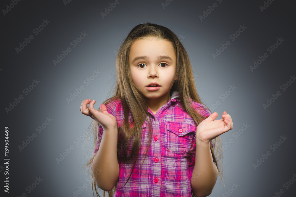 Little girl with astonished expression while standing against grey background Little girl with astonished expression while standing against grey background