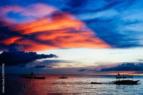 Beautiful, colorful sunset over fishing boats and people in water